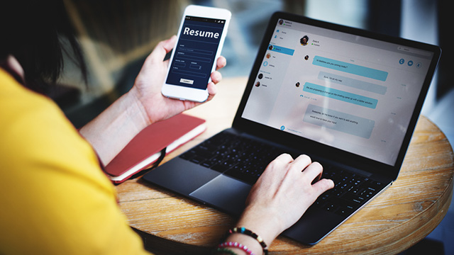 female professional with online resume on cell phone and laptop