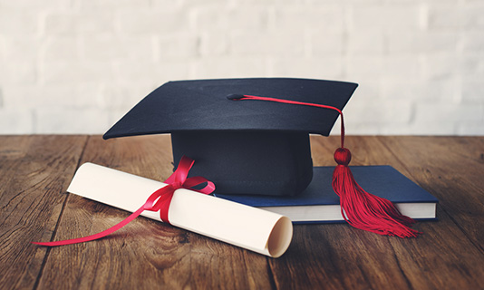 Graduate cap, scroll and textbook
